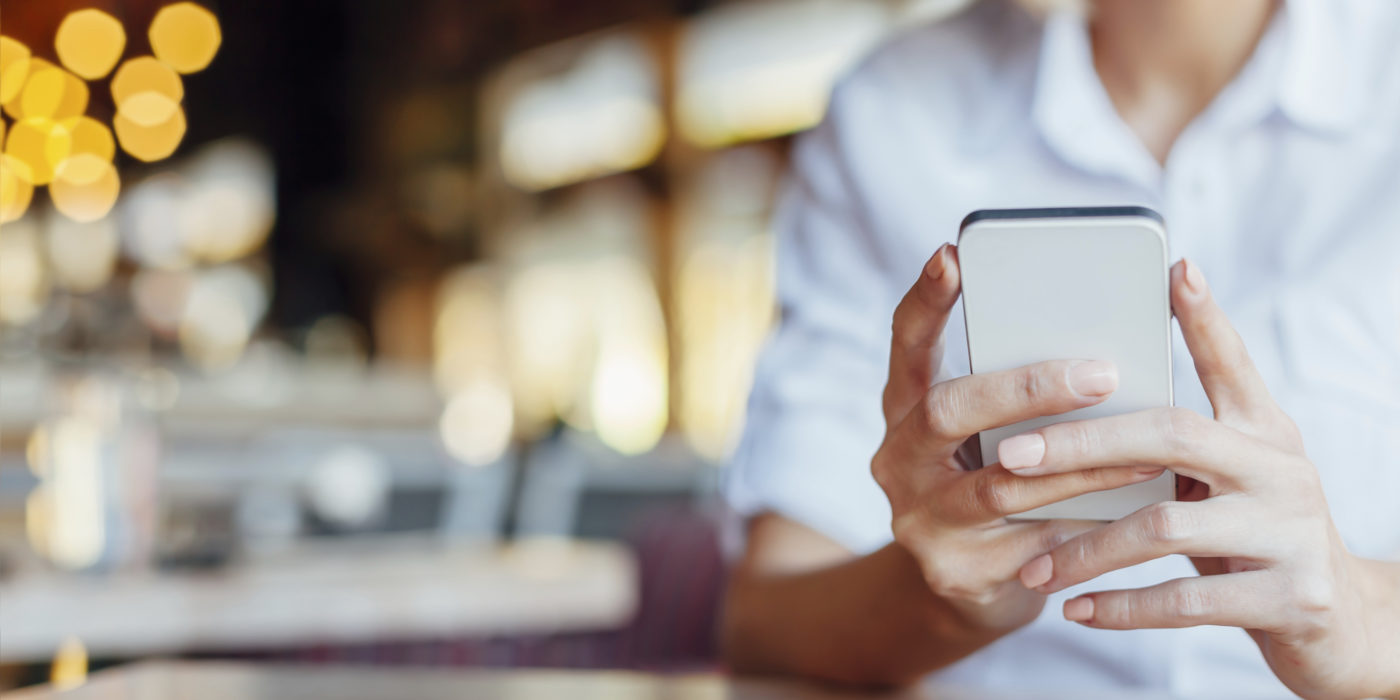 Woman holding mobile phone in a cafe